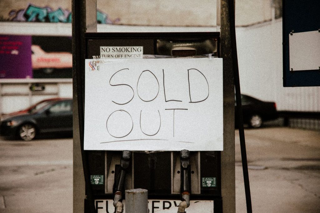 A gas pump at an urban station displaying a Sold Out sign, illustrating fuel shortage.